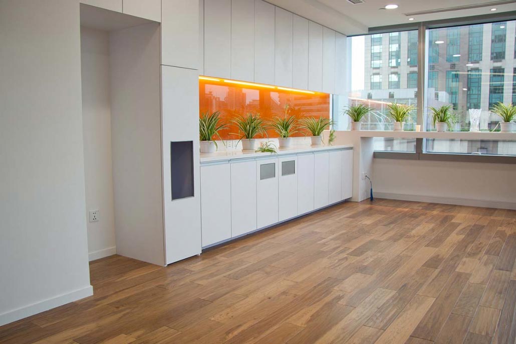 We are the NH laminate floor services authority, providing a multitude of options for businesses and commercial properties statewide. Pictured here is a NH laminate flooring installation we performed last year, the floor resembles authentic wood, and the white cabinetry creates a beautiful accent with the orange wall.